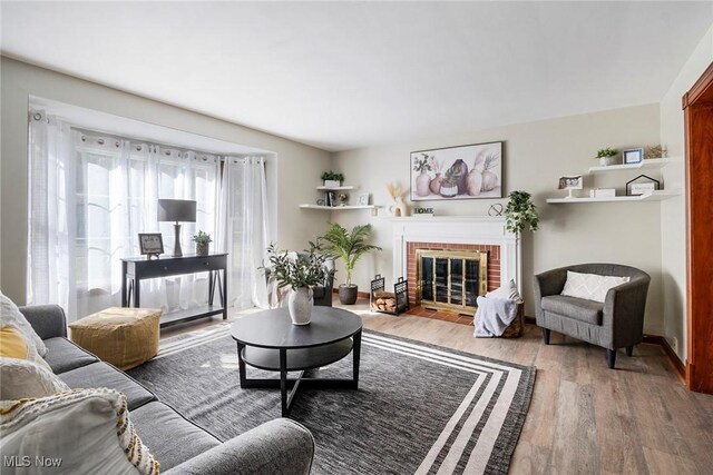 living room featuring wood-type flooring and a brick fireplace