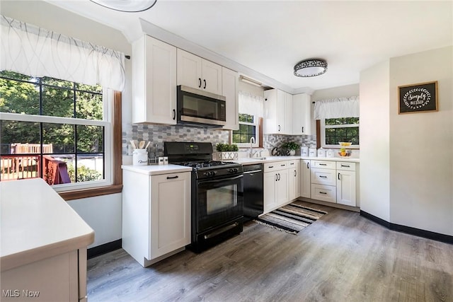 kitchen with decorative backsplash, white cabinets, light countertops, and black appliances