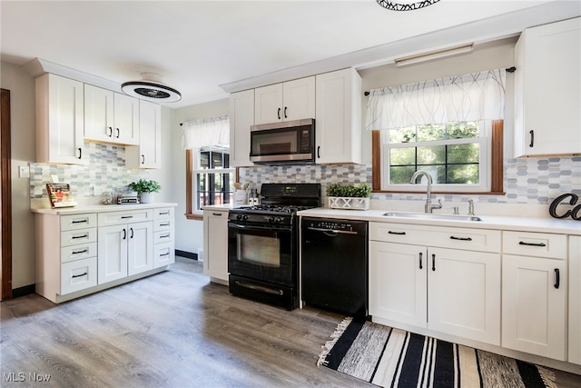 kitchen with sink, white cabinetry, a wealth of natural light, and black appliances