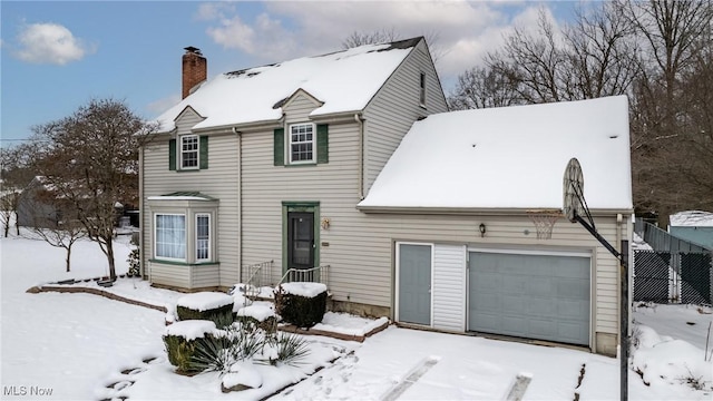 snow covered rear of property with a garage