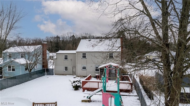 snow covered rear of property featuring a playground