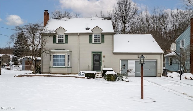 snow covered rear of property with a garage