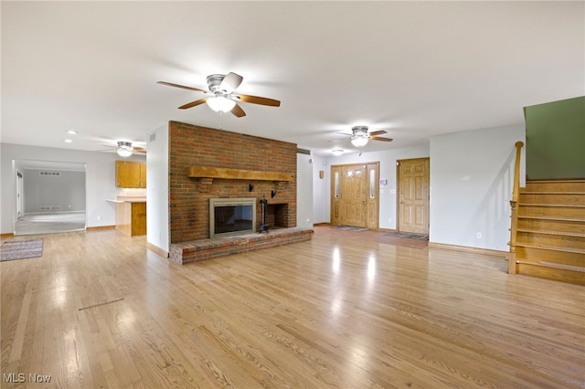 unfurnished living room with a fireplace, light wood-type flooring, and ceiling fan