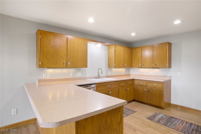 kitchen featuring light wood-type flooring, dishwasher, kitchen peninsula, and sink