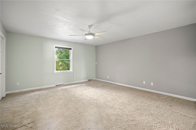 spare room with a textured ceiling, ceiling fan, and light carpet