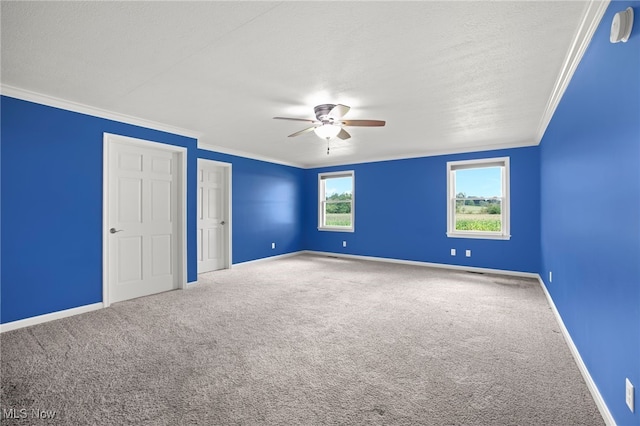 unfurnished bedroom with ornamental molding, a textured ceiling, ceiling fan, carpet flooring, and multiple closets