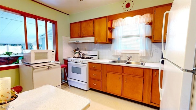 kitchen featuring white appliances, a wealth of natural light, backsplash, and sink