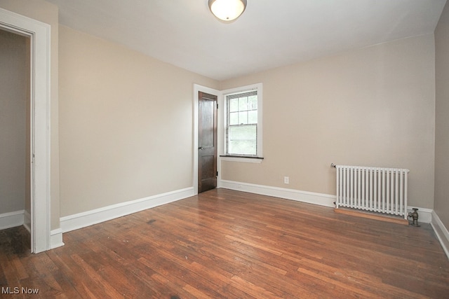 empty room with dark wood-type flooring and radiator heating unit