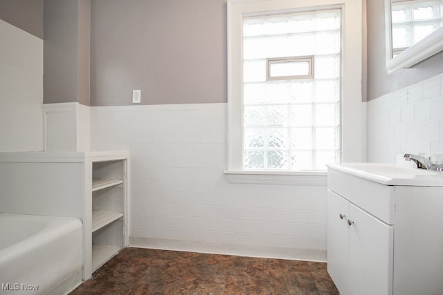 bathroom featuring vanity, tile walls, a healthy amount of sunlight, and a bathtub