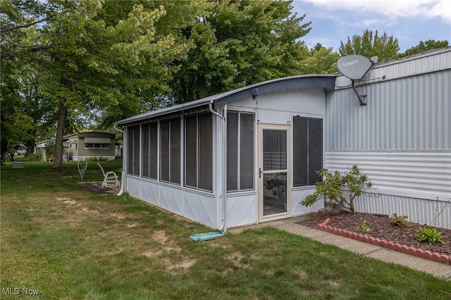 view of outdoor structure featuring a sunroom and a lawn