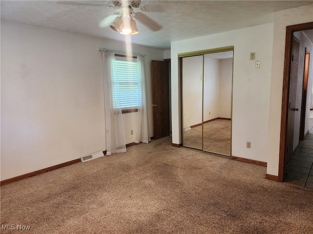 unfurnished bedroom featuring light carpet, a textured ceiling, ceiling fan, and a closet