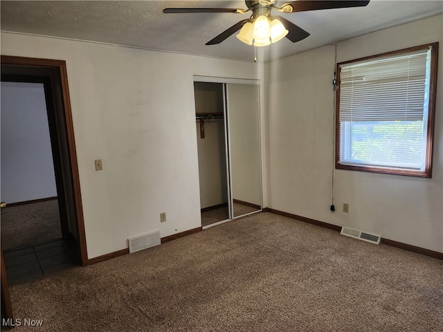 unfurnished bedroom with carpet flooring, a closet, ceiling fan, and a textured ceiling