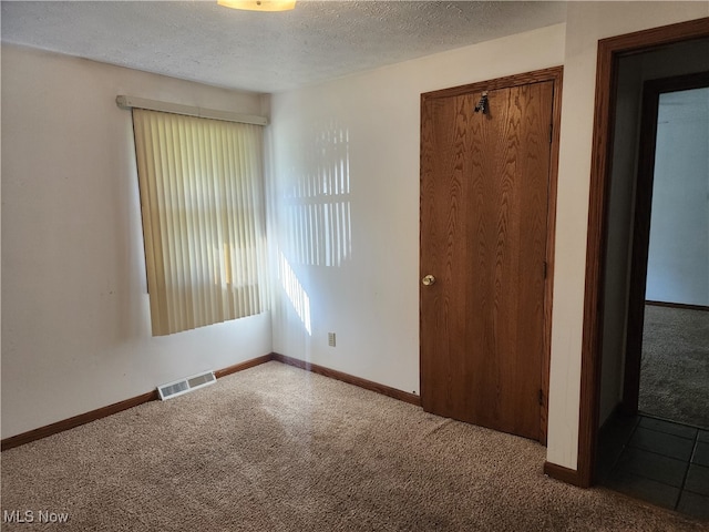 unfurnished bedroom with a closet, a textured ceiling, and carpet