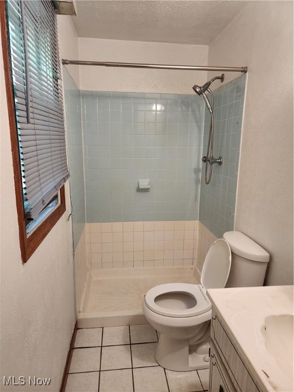 bathroom featuring a textured ceiling, vanity, tiled shower, toilet, and tile patterned floors