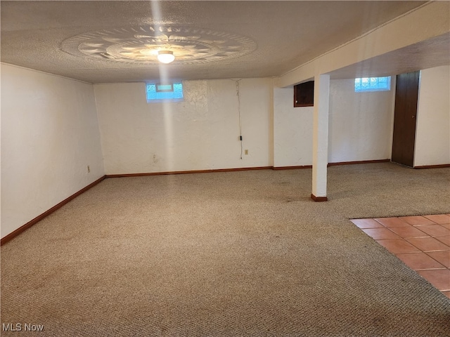 basement with a textured ceiling, carpet flooring, and a wealth of natural light