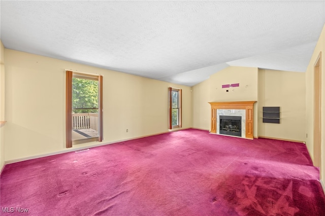 unfurnished living room featuring a high end fireplace, a textured ceiling, lofted ceiling, and carpet floors