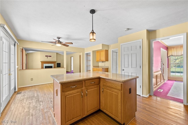 kitchen featuring a kitchen island, ceiling fan, decorative light fixtures, and light hardwood / wood-style floors