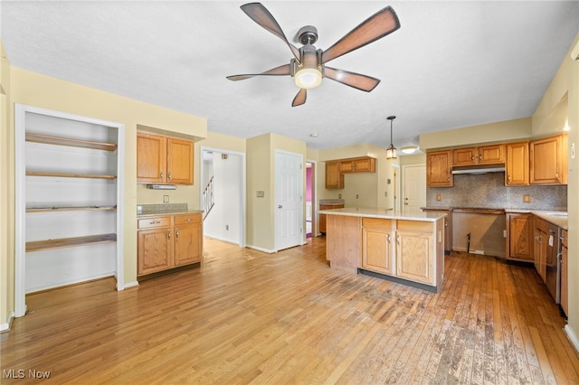 kitchen with a kitchen island, decorative light fixtures, tasteful backsplash, ceiling fan, and light wood-type flooring