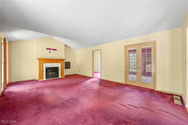 unfurnished living room featuring lofted ceiling, a fireplace, carpet, and french doors