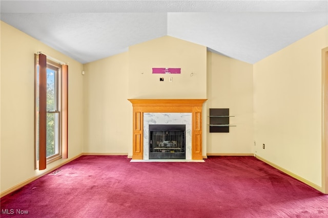 unfurnished living room featuring carpet floors, a wealth of natural light, a high end fireplace, and vaulted ceiling