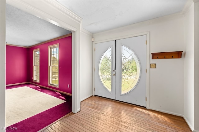 foyer entrance featuring french doors, ornamental molding, and light hardwood / wood-style flooring