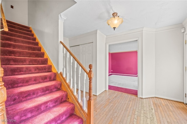 stairs with crown molding and hardwood / wood-style floors