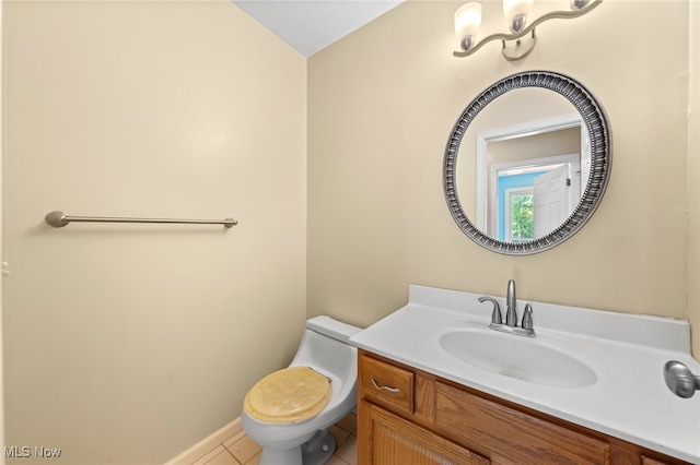 bathroom with tile patterned flooring, vanity, toilet, and a textured ceiling