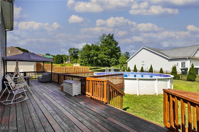 wooden terrace featuring a lawn, a fenced in pool, and a gazebo