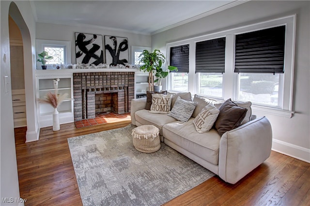 living room with dark hardwood / wood-style flooring, crown molding, and a brick fireplace