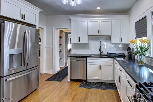 kitchen featuring appliances with stainless steel finishes, light hardwood / wood-style floors, sink, decorative backsplash, and white cabinetry