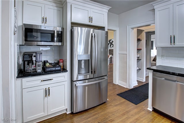 kitchen featuring white cabinets, appliances with stainless steel finishes, hardwood / wood-style floors, and decorative backsplash