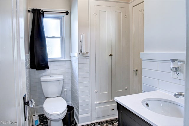 bathroom with vanity, toilet, and tile walls