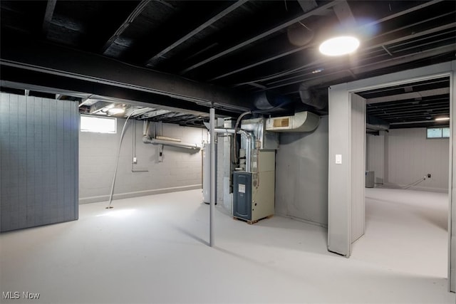 basement featuring a wealth of natural light, heating unit, and water heater