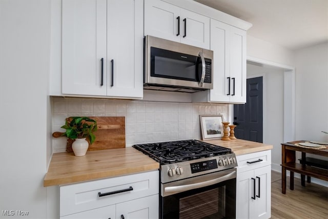 kitchen featuring white cabinetry, light hardwood / wood-style flooring, butcher block counters, backsplash, and appliances with stainless steel finishes