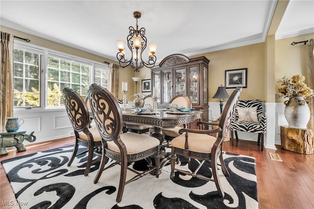 dining area with ornamental molding, dark wood-type flooring, and a chandelier