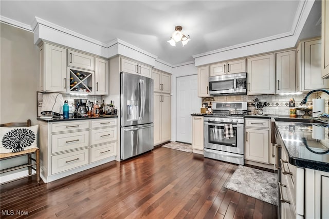 kitchen featuring ornamental molding, appliances with stainless steel finishes, cream cabinets, and dark hardwood / wood-style floors