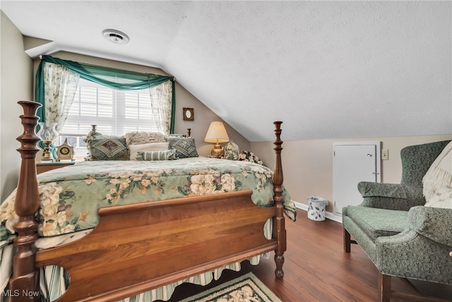 bedroom with lofted ceiling, hardwood / wood-style flooring, and a textured ceiling