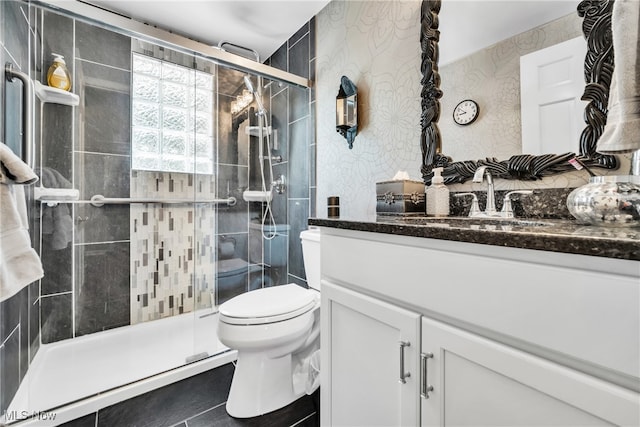 bathroom featuring vanity, toilet, tile patterned flooring, and a shower with door