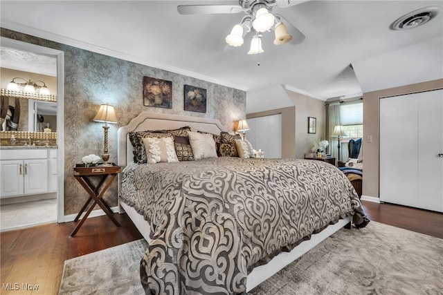 bedroom with hardwood / wood-style flooring, ensuite bathroom, a closet, ceiling fan, and ornamental molding