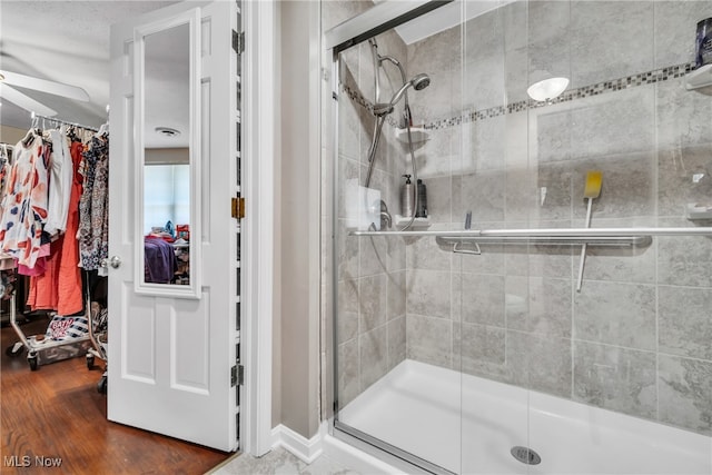 bathroom featuring ceiling fan, walk in shower, and wood-type flooring