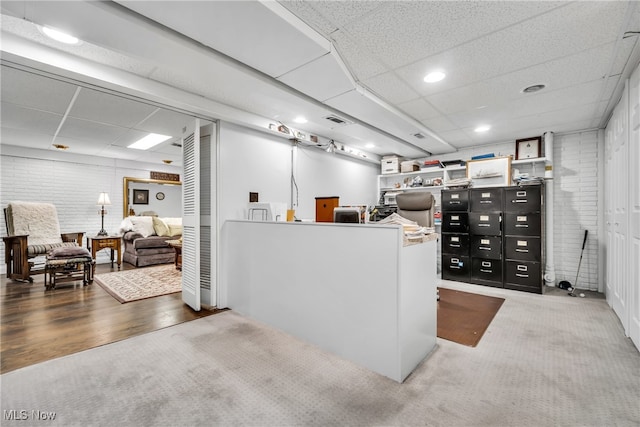 interior space with a paneled ceiling and hardwood / wood-style flooring