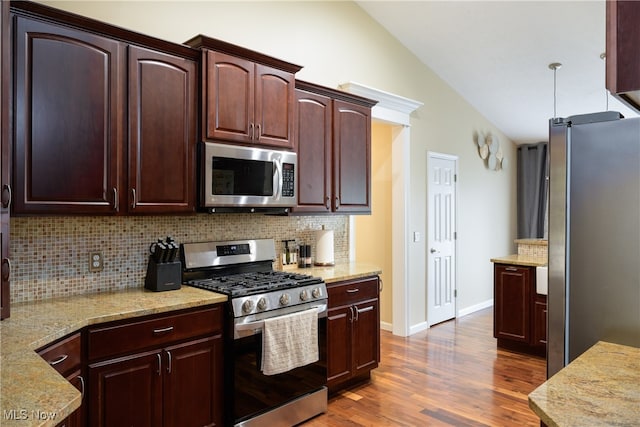 kitchen featuring light stone countertops, stainless steel appliances, lofted ceiling, dark hardwood / wood-style floors, and tasteful backsplash