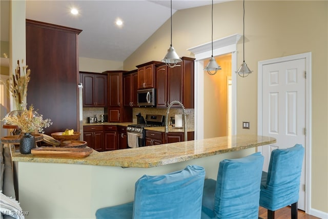 kitchen with pendant lighting, appliances with stainless steel finishes, a breakfast bar, decorative backsplash, and light stone counters