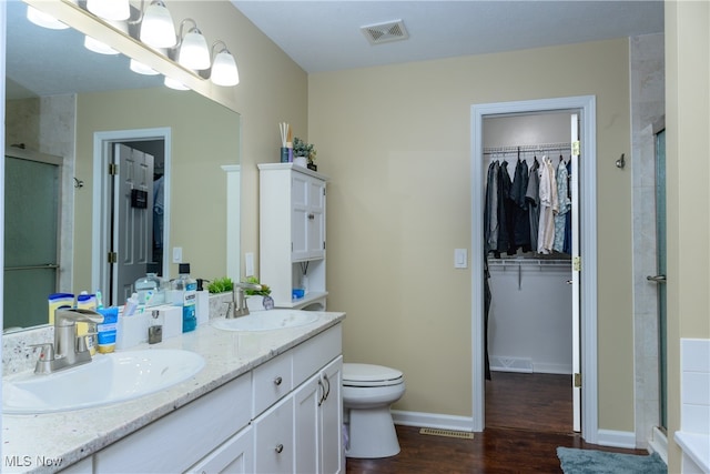 bathroom featuring vanity, toilet, wood-type flooring, and walk in shower