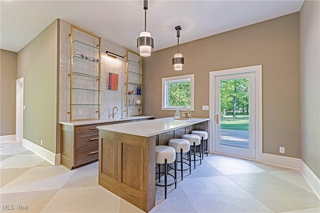 kitchen with pendant lighting, a kitchen bar, kitchen peninsula, and sink