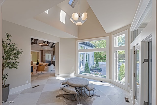 sunroom with plenty of natural light, lofted ceiling with beams, and a notable chandelier