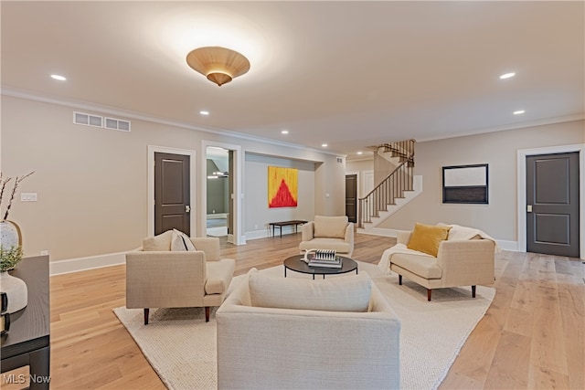 living room with ornamental molding and light hardwood / wood-style flooring