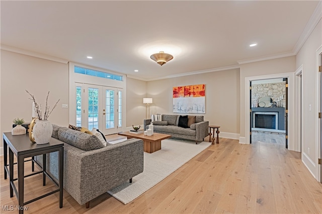 living room featuring light hardwood / wood-style floors, french doors, ornamental molding, and a stone fireplace