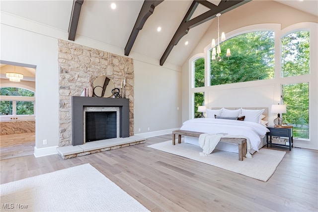 bedroom with a fireplace, light hardwood / wood-style floors, beamed ceiling, high vaulted ceiling, and a chandelier