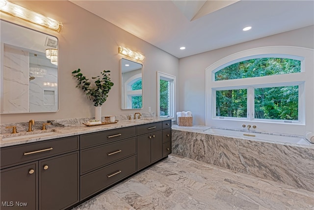 bathroom with lofted ceiling, vanity, plenty of natural light, and a washtub